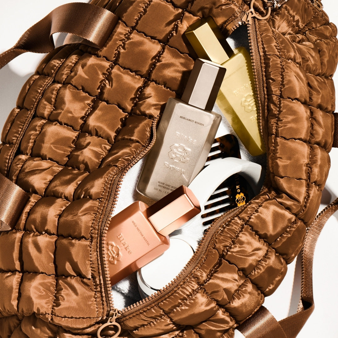 Blake Brown Hair and Body Refresh Mists in assorted scents packed inside a brown quilted bag, with a branded wide-tooth comb and white towel—an effortless on-the-go beauty routine.