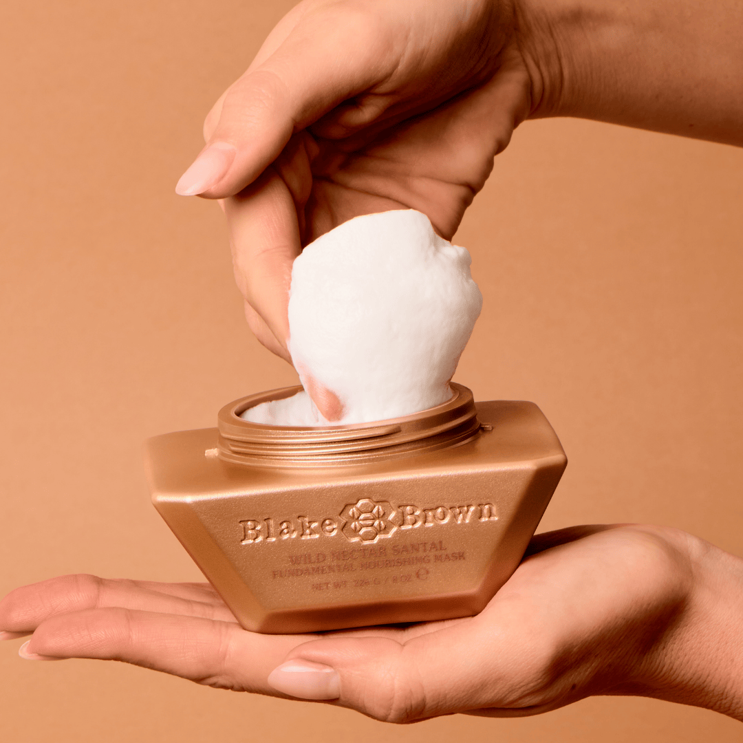 Hand scooping Blake Brown Nourishing Mask from gold jar.