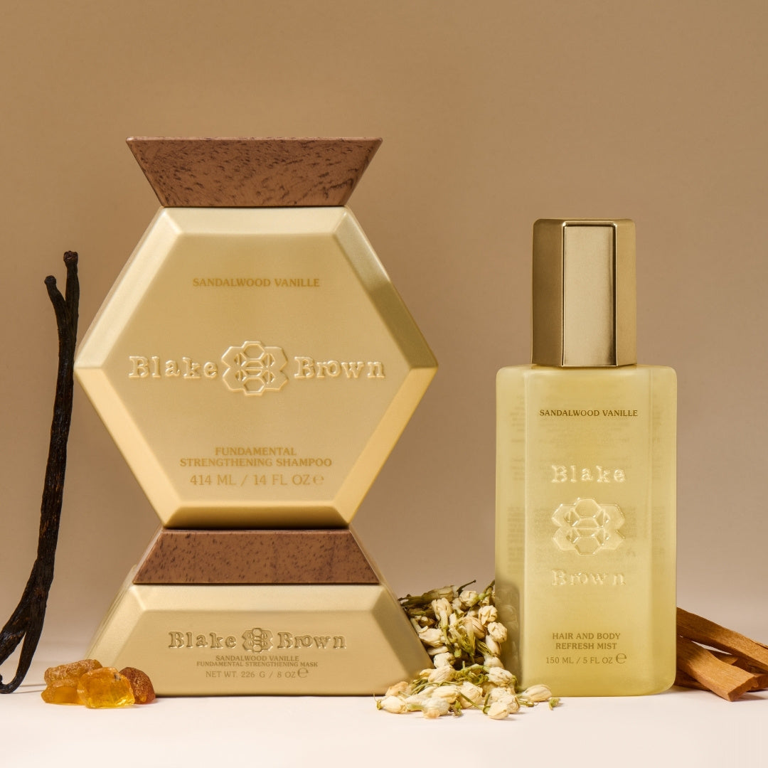 Blake Brown Sandalwood Vanille haircare trio—Strengthening Shampoo, Strengthening Mask, and Hair and Body Refresh Mist—styled with vanilla beans, dried florals, and amber on a beige background.