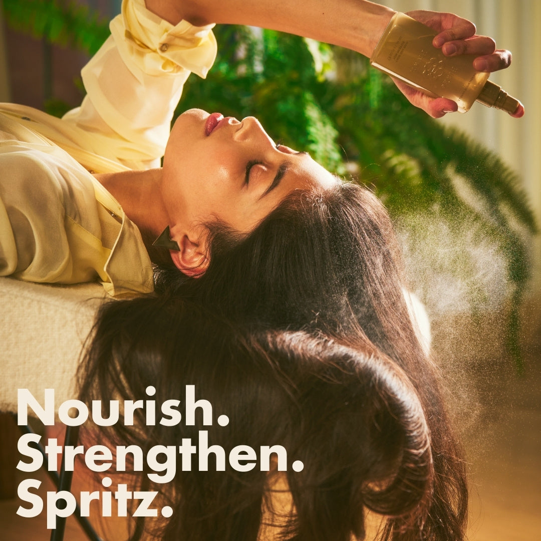 Woman reclining with long hair while spraying Blake Brown Hair and Body Refresh Mist, with bold text overlay reading “Nourish. Strengthen. Spritz.” and greenery in the background.