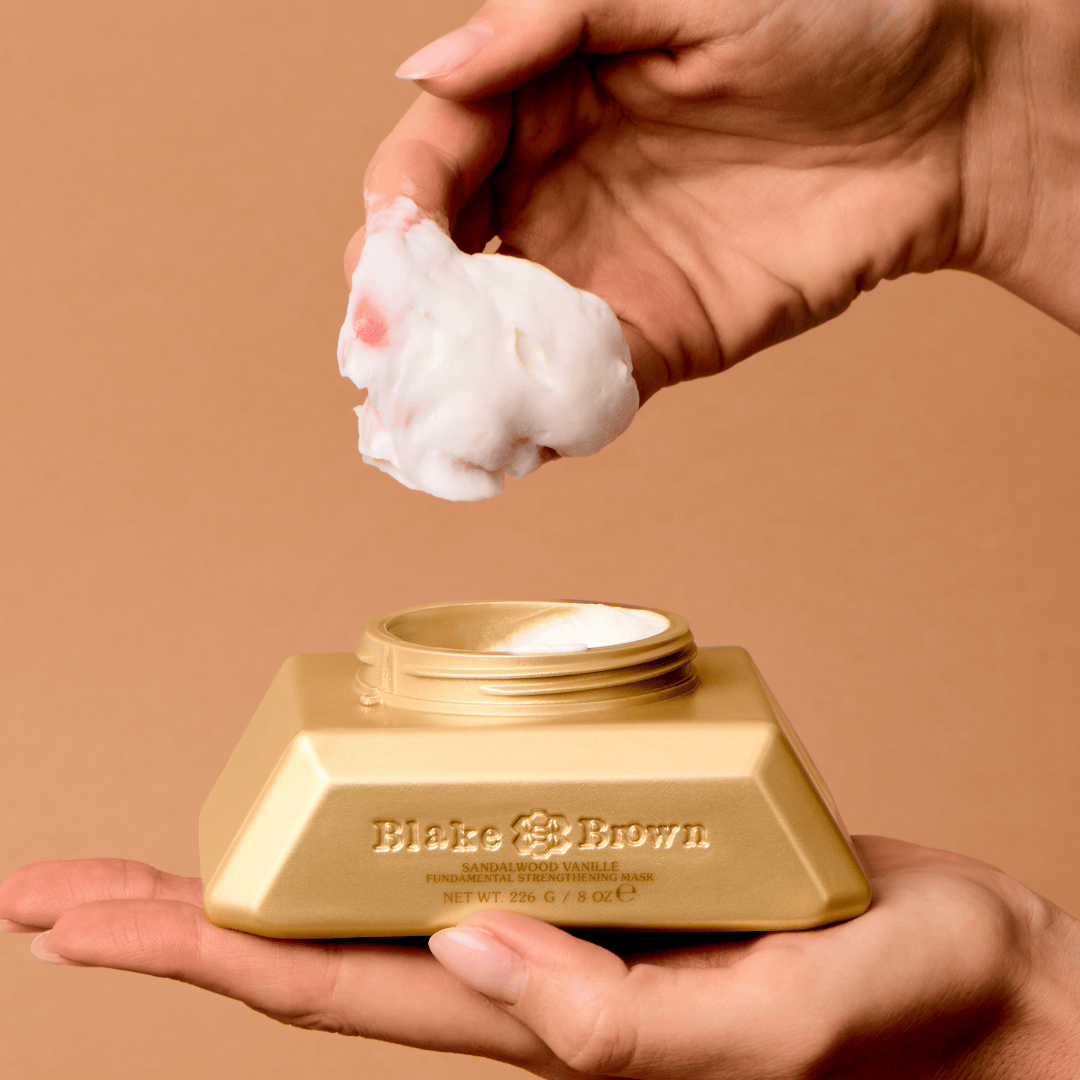 Hand scooping Blake Brown Sandalwood Vanille Strengthening Mask from gold jar.