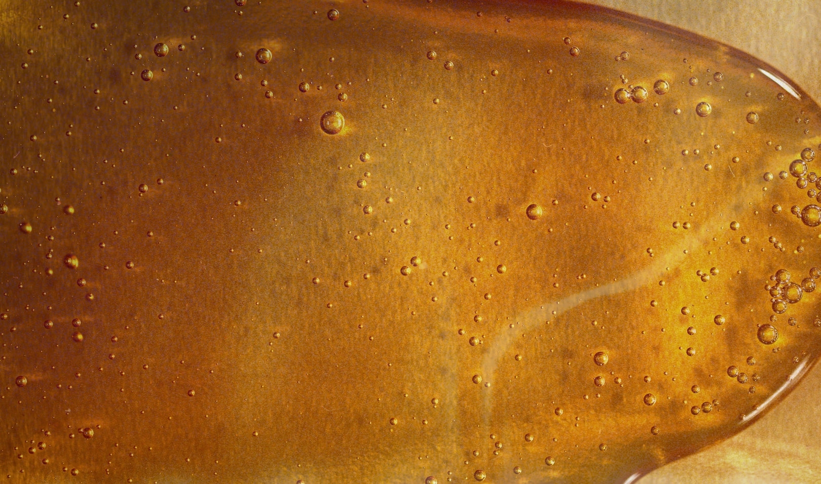 A rich honey-colored surface with glistening bubbles, evoking the essence of Blake Brown's Wild Nectar Santal fragrance.