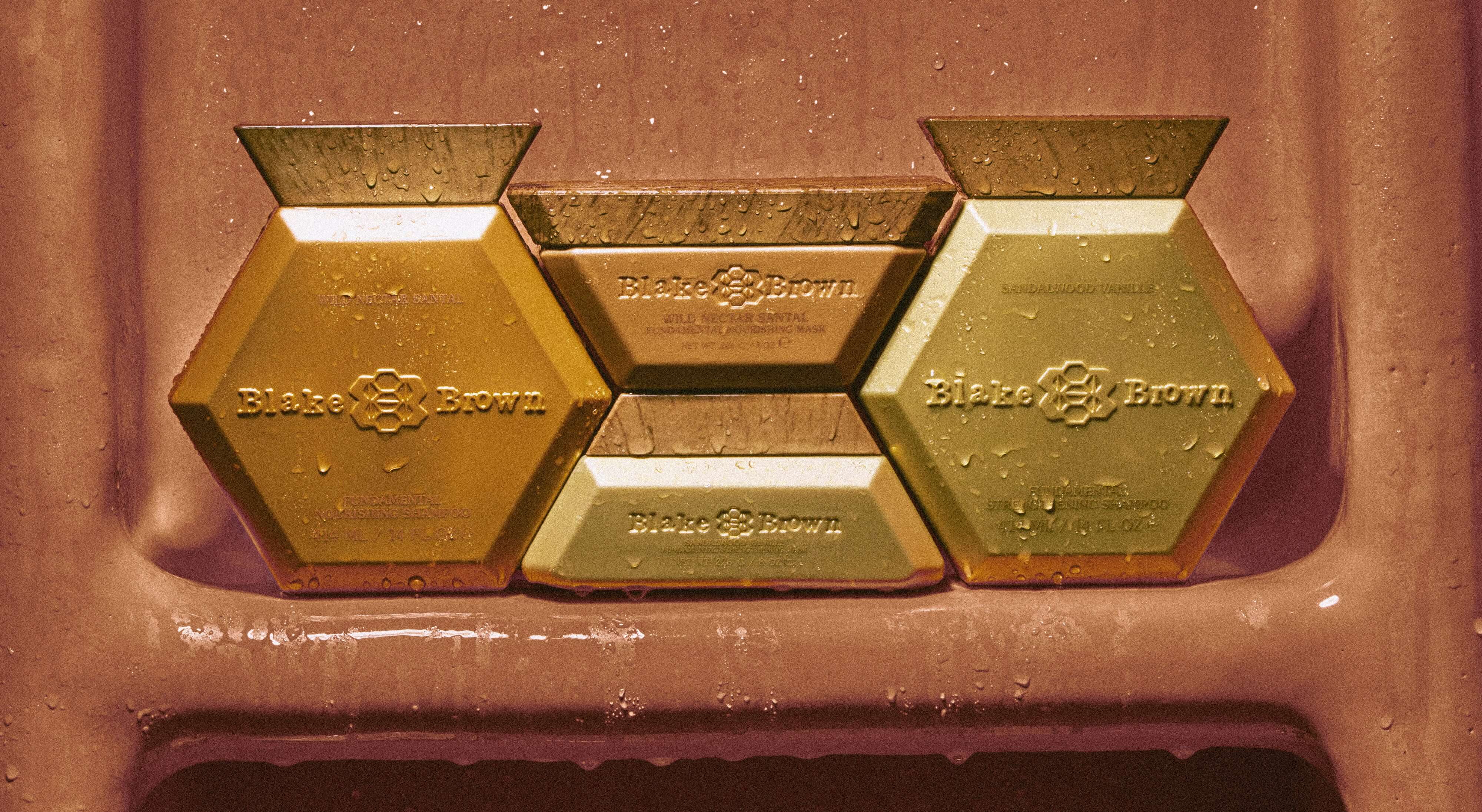 Blake Brown Nourishing and Strengthening Shampoo and Mask Hair System by Blake Lively, arranged artfully on a wet surface to highlight its luxurious design.
