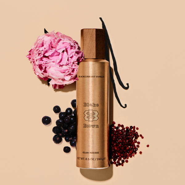 Blake Brown Glam Mousse styled with blackcurrant, pink peppercorn, vanilla, and a pink peony to highlight its Blackcurrant Vanille fragrance.