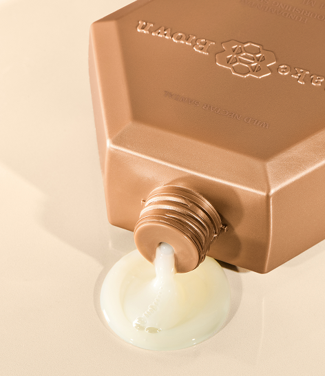 Blake Brown Nourishing Shampoo pouring from a bronze hexagonal bottle onto a smooth surface.