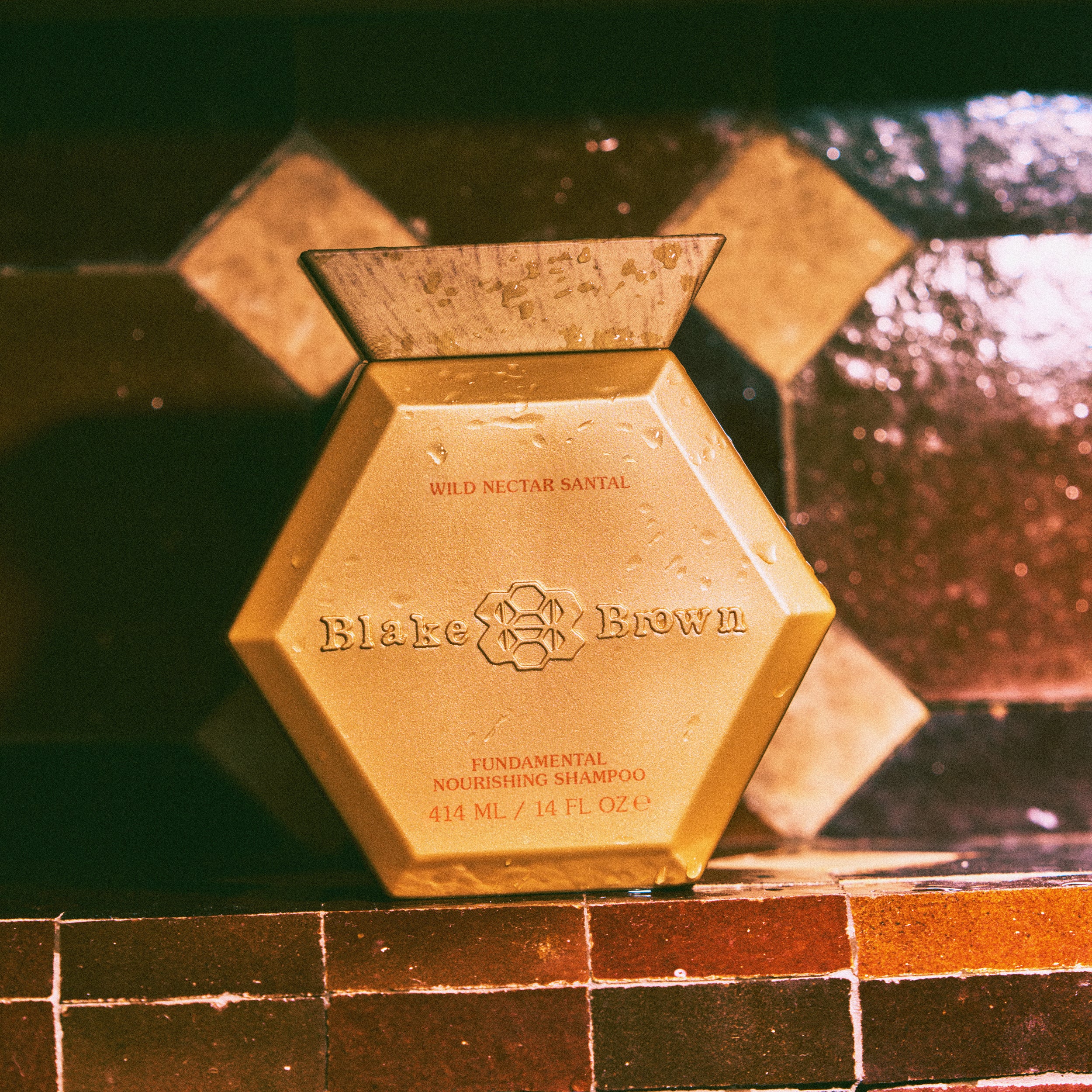 Blake Brown Wild Nectar Santal Fundamental Nourishing Shampoo by Blake Lively, covered in water droplets to emphasize its hair-hydrating effects.